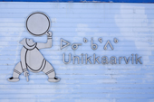 The sign for the Unikkaarvik Visitors Center in Iqaluit, with drum singer logo and syllabics. Nunavut. Canada. 2008