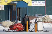 Petrol or Gas Pump attendant fills a snowmobile with gas before the weekend. Iqaluit. Nunavut. Canada. 2008