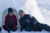 Inuit boy Gilbert Augsaq in blue, and a young friend, investigate an igloo built on Hamlet Day, Igloolik. Nunavut, Canada. 2008