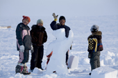 Inuit girls and boys gather round a snow dancing bear on Hamlet Day. Igloolik, Nunavut, Canada. 2008