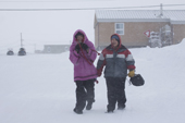 Inuit youth wears a pink amautik in a snowstorm, he is babysitting a younger member of the family. Igloolik. Nunavut, Canada. 2008