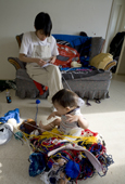 Inuit mother Sula Qumangat makes a crochet hat for her son Thomas Roger, while he plays with some wool. Igloolik. Nunavut, Canada. 2008