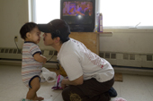 Gus with his son Thomas Roger by the TV in their home. Igloolik, Nunavut, Canada. 2008