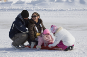 Inuit girl laughs with a young man while playing on a tobbogan. Igloolik, Nunavut, Canada. 2008
