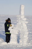An Inuit boy building an Inukshuk from snow as part of the celebrations for Hamlet Day in Igloolik. Nunavut, Canada. 2008