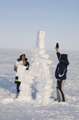 Inuit boys measuring an Inukshuk from snow as part of the celebrations for Hamlet Day in Igloolik. Nunavut, Canada. 2008