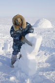 An Inuit man, Serapio Ittusardjuat, using a saw to make a dancing bear out of snow. Igloolik. Nunavut, Canada. 2008