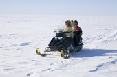Jaipiti Palluq, an Inuit hunter from Igloolik, driving a snowmobile on the sea ice with his son Abel on the back. Igloolik, Nunavut, Canada. 2008