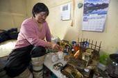 In her hut at an outpost camp, Kanguq (Eunice) an elderly Inuit woman, tends the flame of a Qulliq (seal oil lamp). Igloolik, Nunavut, Canada. 2008