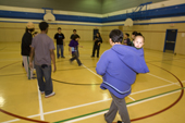 Inuit mother with her baby in an amuatiq watches Inuit youngsters taking part in a Hip hop dance class in the school gymnasium at Pangnirtung, Nunavut, Canada. 2008