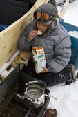 Aidan, an Inuit boy from Pangnirtung, eats potato chips while out seal hunting with his parents in Cumberland Sound. Nunavut, Canada. 2008