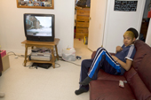 Gordon Metuq, a young Inuit boy watching TV at his home in Pangnirtung. Nunavut, Canada. 2008