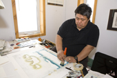 Inuit artist, Andrew Qappik, works on a stencil print at the Uqqurmiut Centre for Arts and Crafts in Pangnirtung. Nunavut, Canada. 2008