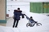 An young Inuit woman pushes her child in a pram in the community of Pangnirtung. Nunavut, Canada. 2008