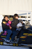 Two young Inuit woman with their children on a snowmobile in Pangnirtung. Nunavut, Canada. 2008