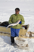 An Inuit woman poses with an Arctic Char she has caught on a lake near Pangnirtung. Nunavut, Canada. 2008