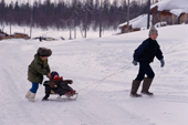 An Evenki boy and girl pulling a baby on a toboggan in Surinda. Evenkiya, Siberia, Russia. 1997