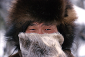 In the cold of winter, Andrei Dulubchin, an Evenki man warms his nose with his reindeer skin mitten. Evenkiya, Siberia, Russia. 1997