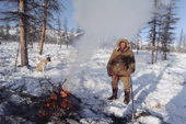 Andrey Apoka, an Even reindeer herder warms himself by an open fire at winter pastures. N.Evensk, Magadan, E. Siberia, Russia. 2006