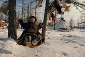 A Nenets boy plays on a swing at a reindeer herders' winter camp. Yamal. Siberia. Russia.