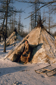 Ludmilla Serotetto, a Nenets woman emrges from a reindeer skin tent at a herders' winter camp. Yamal, Siberia, Russia.