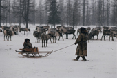 A Nenets woman gives her young son a sled ride at a reindeer herders' winter camp. Yamal, Siberia, Russia