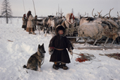 Pudako Serotetto, a young Nenets boy, standing by a corral with a young Laika reindeer herding dog on the spring migration. Yamal. Siberia. Russia.