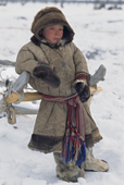 Boris Serotetto, a young Nenets boy in traditional dress, leans against a reindeer sled at a herders' camp in the Yamal. Western Siberia, Russia.