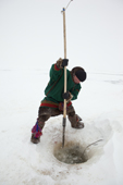 Pyotr Serotetto, a young Nenets man, opens a hole in the ice to check his fishing net. Seyakha, Yamal Peninsula, Western Siberia