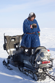 Jakov Vanuito, a Nenets man, stands on his snowmobile seat to get a better signal on his mobile phone. Seyakha, Yamal Peninsula, Western Siberia, Russia