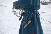A Nenets reindeer herder wearing traditional dress coils his lasso. A knife is hanging from his belt. Tambey, Yamal Peninsula, Western Siberia, Russia
