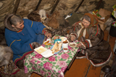 Vadim Vengy, a Nenets reindeer herder, having a meal with 76 year old Nyaka inside her reindeer skin tent. Tambey, Yamal Peninsula, Western Siberia, Russia