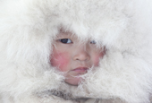Nenya Vanuito, a young Nenets girl, wearing a traditional hat with fur trim at a winter camp near Tambey. Yamal Peninsula, Western Siberia, Russia.
