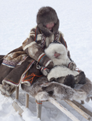 Emma Vanuito, a Nenets woman, holds her daughter, Nenya, while travelling on a sled near their winter camp near Tambey. Yamal Peninsula, Western Siberia, Russia.